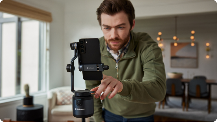 A man operating a Matterport Axis with phone on a tripod.